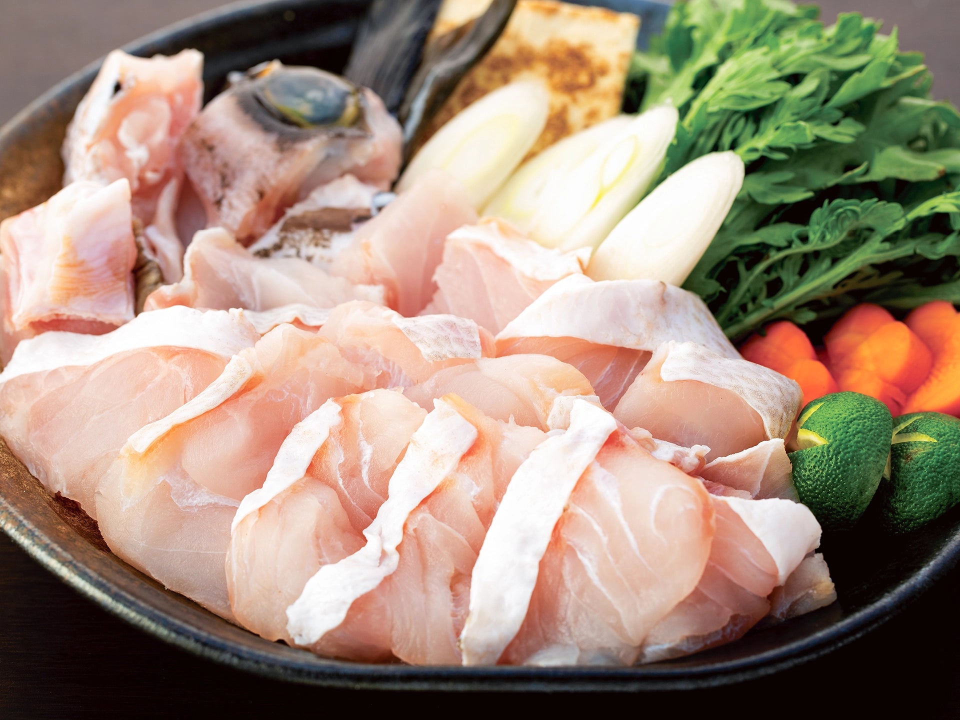 皿に生のクエ、にんじん、ネギ、椎茸、豆腐などが盛られている。